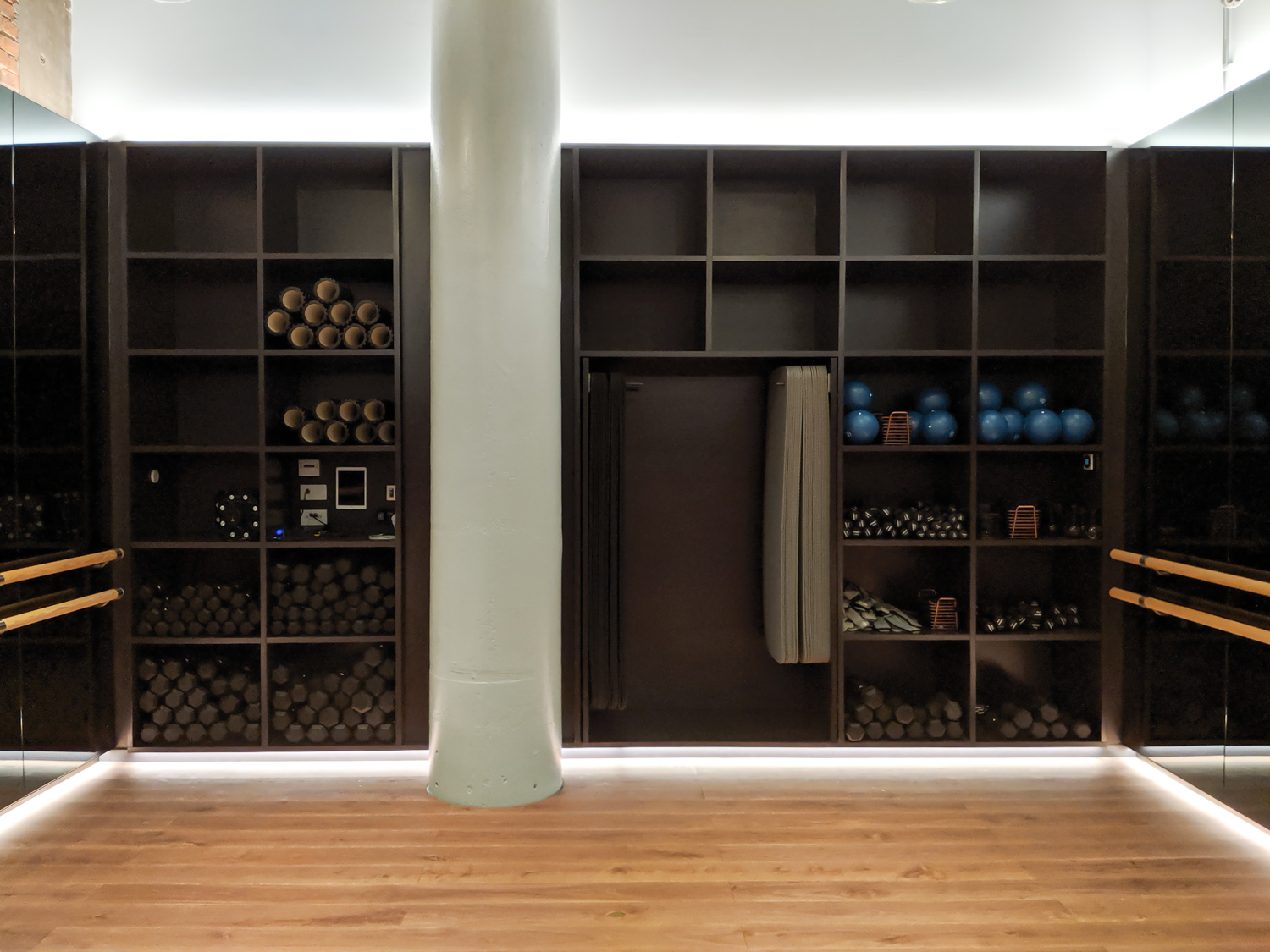 STUDIO 1, 3.5 x 5m Valchromat shelving unit with slide out yoga mat holders and media centre. 
