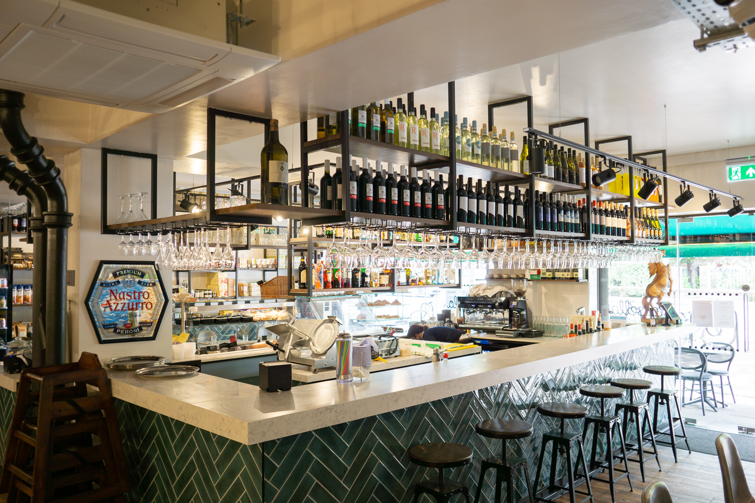 Main Bar, Formica Aria worktops with drop edge. Bar frame, skirting and kick rail all powder coated mild steel. Gantries with stained oak shelves. Bar stool tops.
